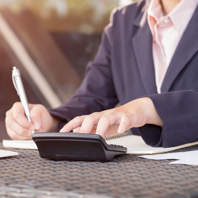 Business professional in suit writing notes with pen at desk with phone