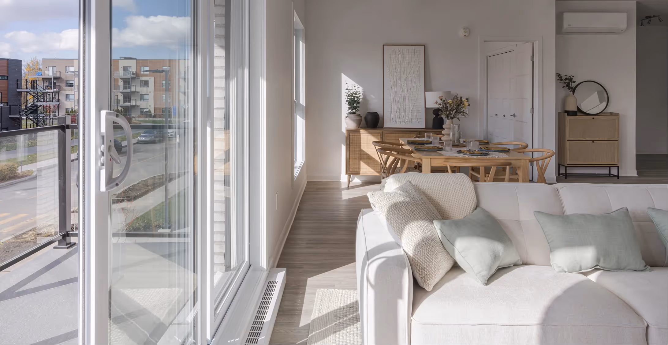 Bright living room with white sofa, wooden dining area and balcony access