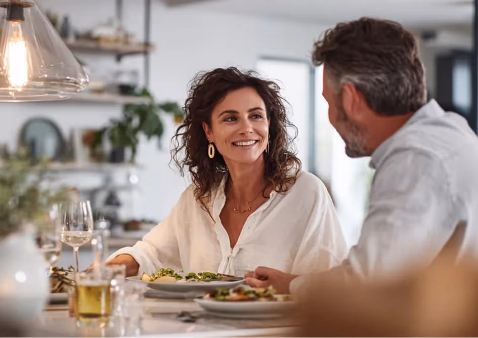 Smiling couple sitting at the table for a meal in a bright kitchen