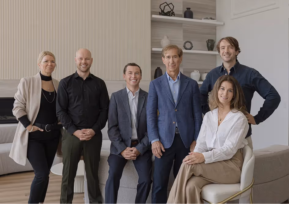 Team of six professionals posing together in a modern space