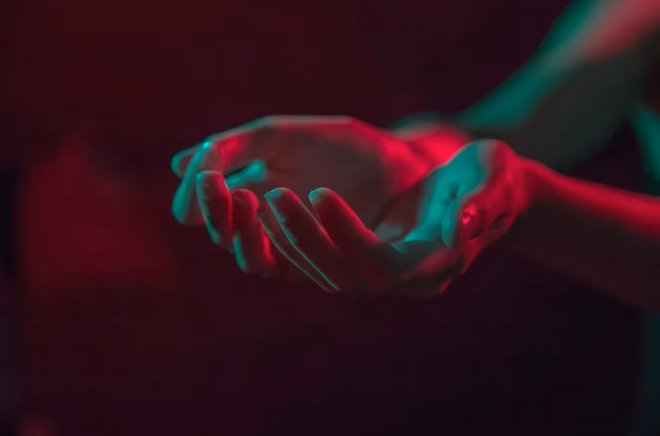 Deux mains ouvertes éclairées par des lumières néon rouges et vertes