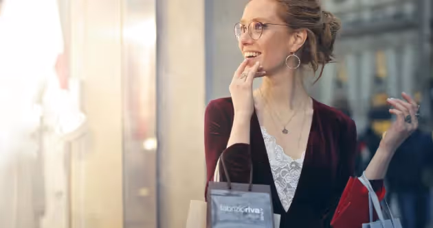 Femme souriante faisant du shopping avec des sacs dans une rue commerçante