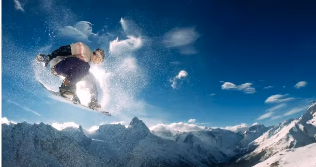 Snowboardeur effectuant un saut au-dessus de sommets enneigés