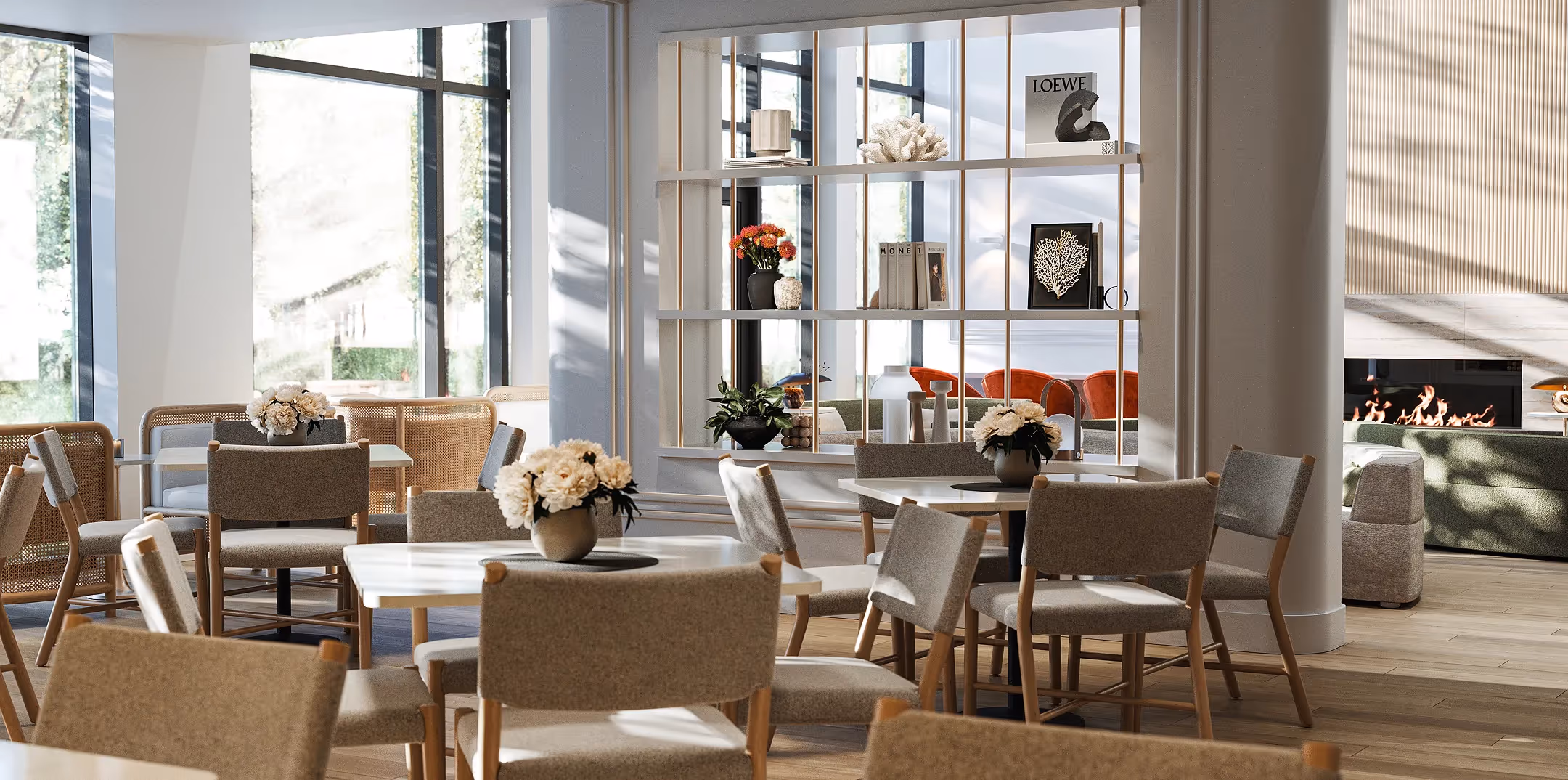 Espace commun lumineux du Nest Immobilier avec tables rondes, chaises en rotin et cheminée