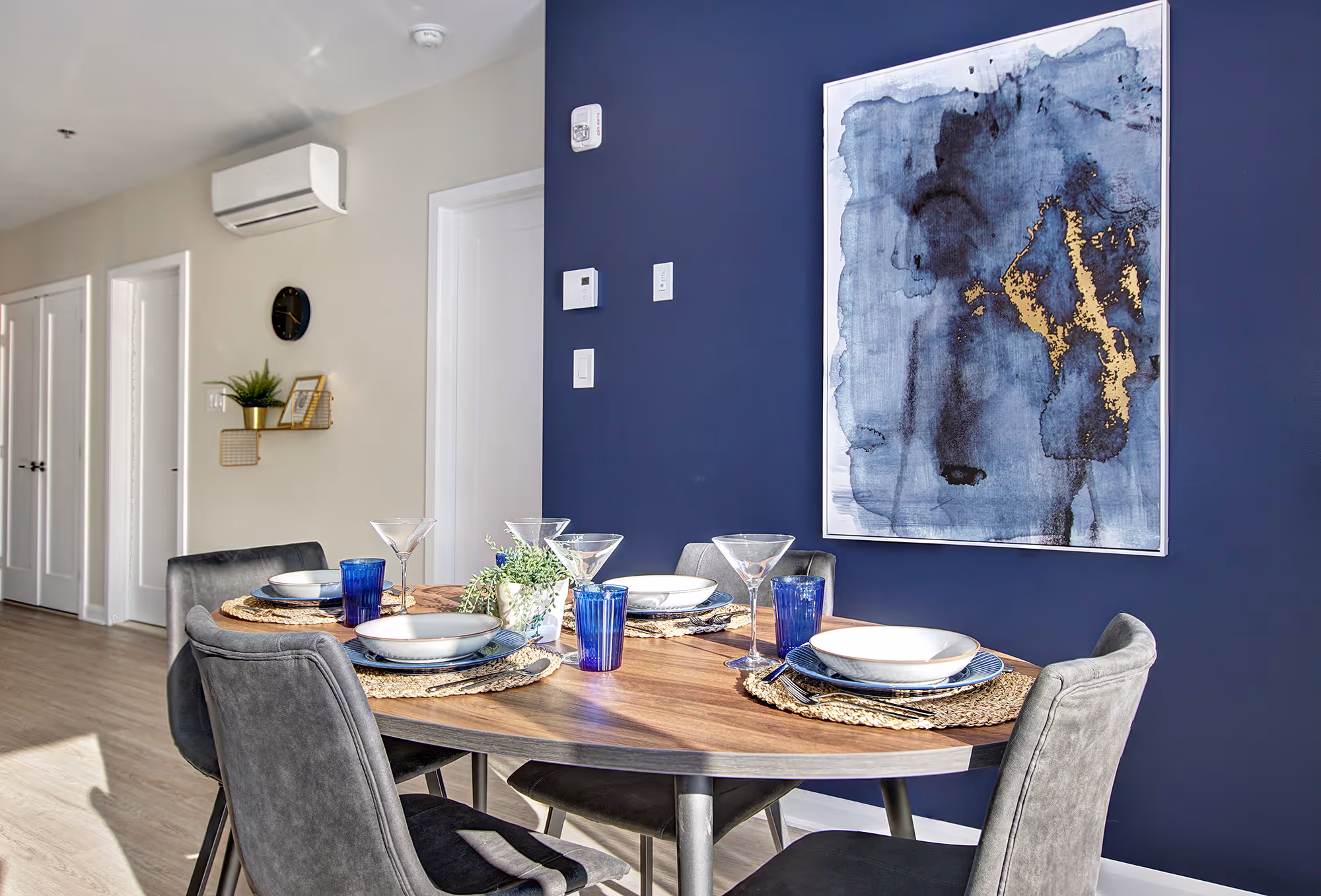Salle à manger du Quartier Vauquelin avec table en bois, chaises grises et mur d'accent bleu marine