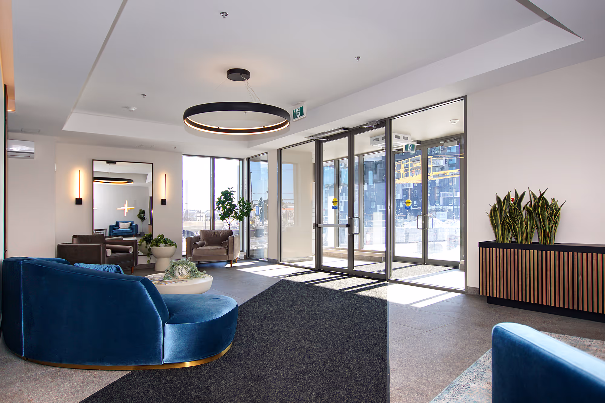 Modern entrance hall with curved blue sofa, armchairs and circular chandelier