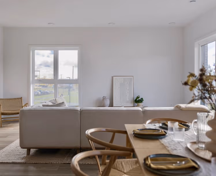 Minimalist living room with grey sofa, wooden dining table and understated decor