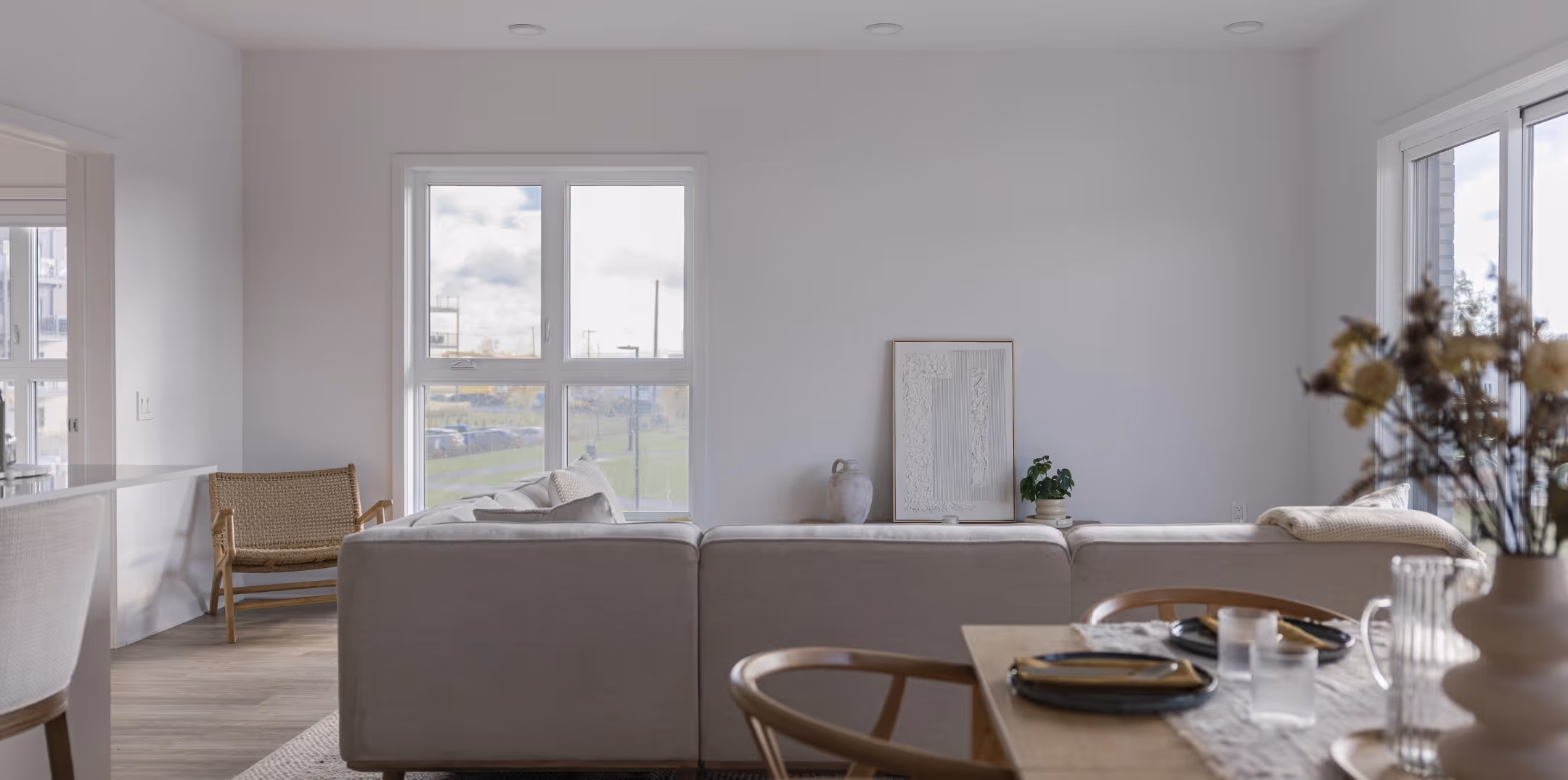 Séjour épuré du Quartier Vauquelin avec canapé beige, table à manger et décoration minimaliste