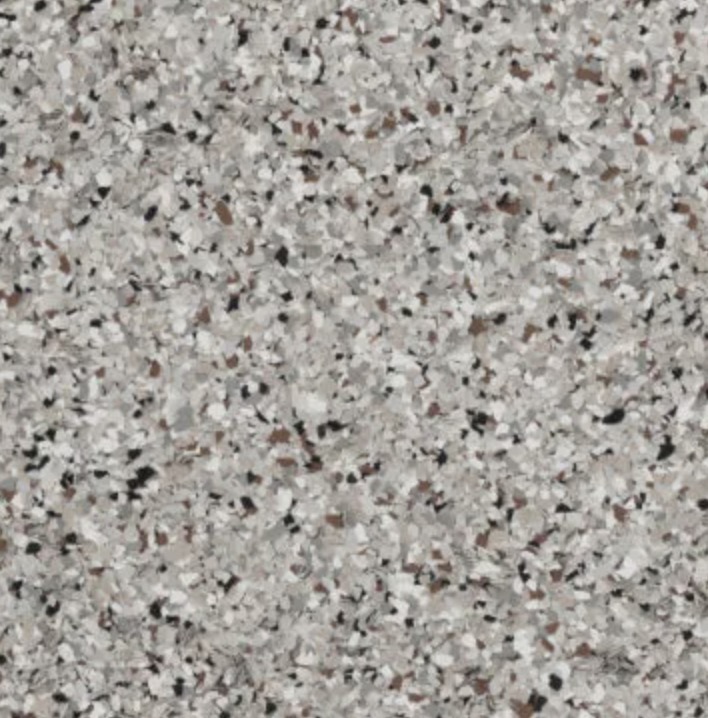 Modern backyard patio with pebble stone ground, outdoor sofa set, fire pit, barbecue grill, and green trees under a clear sky.