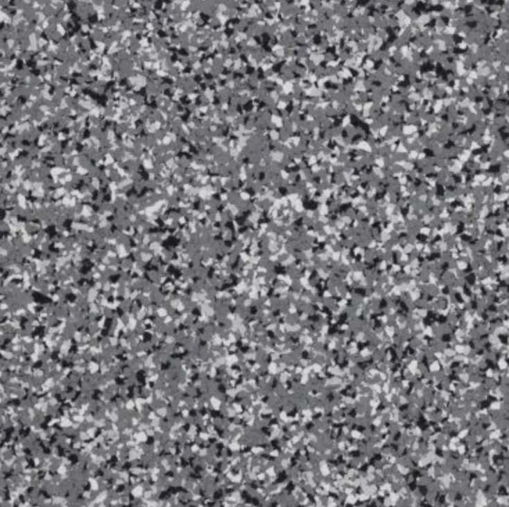 Golden retriever sitting on a polished terrazzo floor in a modern home with a curved staircase and stone accent wall.