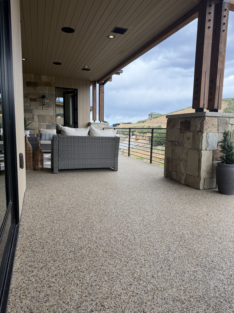 Golden retriever sitting on a polished terrazzo floor in a modern home with a curved staircase and stone accent wall.