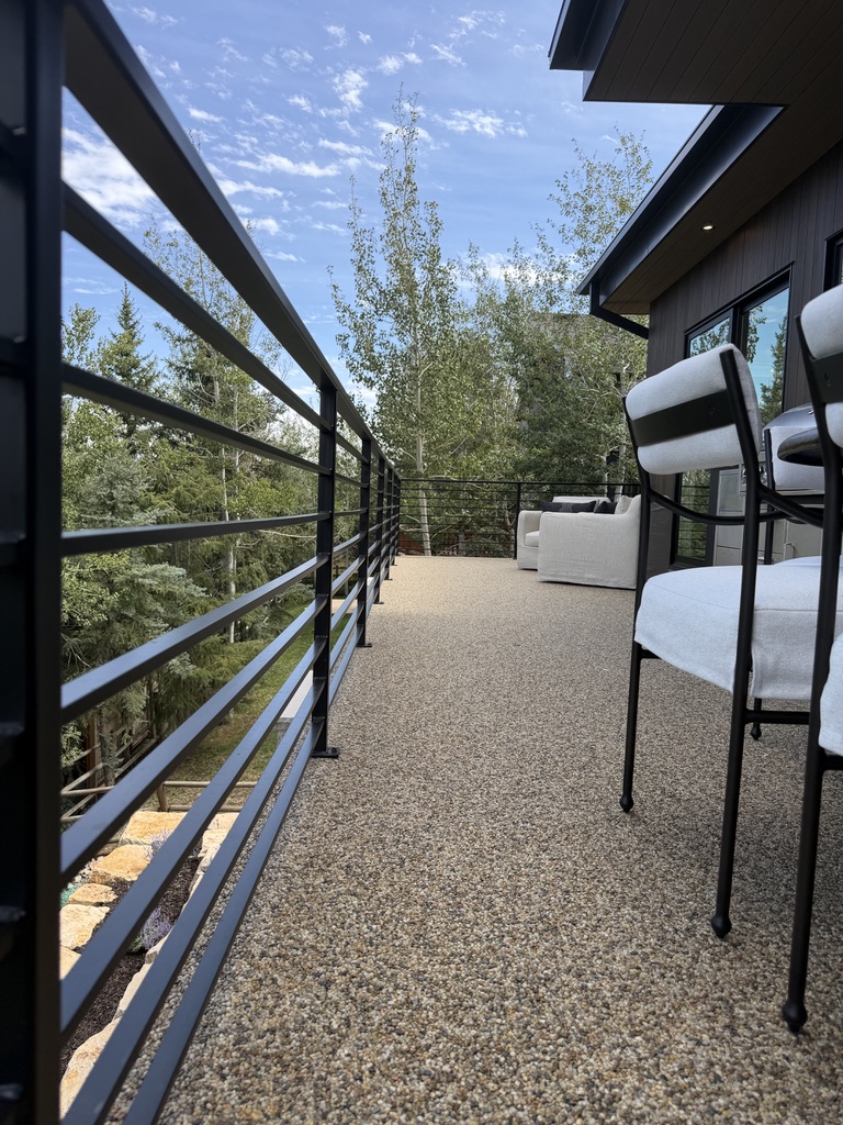 Modern garage with a shiny epoxy resin floor housing a silver sports car, a black sedan, and a green off-road vehicle.