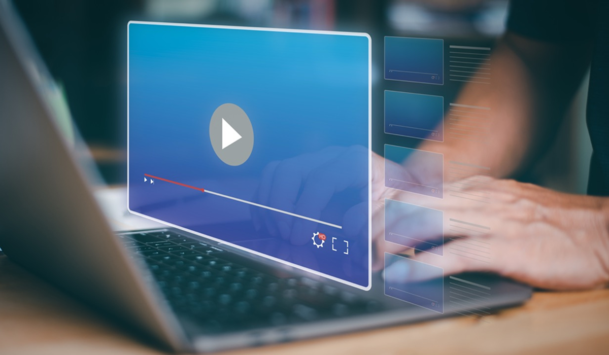 Person using a laptop with a video player and thumbnail playlist overlaid on the screen.