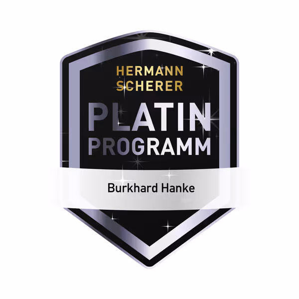 Schwarzes und silbernes Abzeichen mit goldenem Schriftzug Hermann Scherer, Platin Programm und Name Burkhard Hanke.