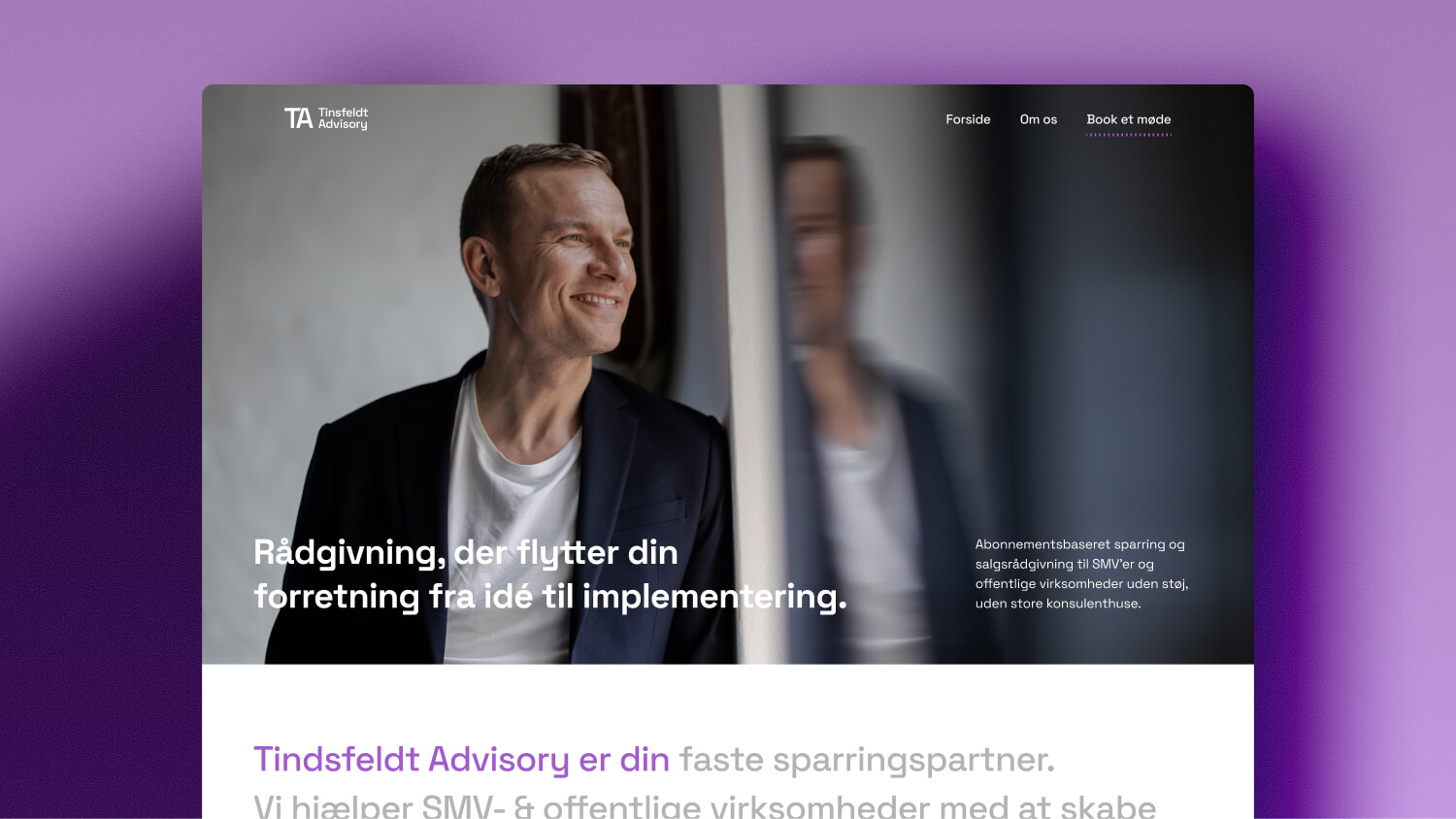 Smilende mand i sort blazer og hvid t-shirt, der kigger ud ad et vindue med sin refleksion synlig.