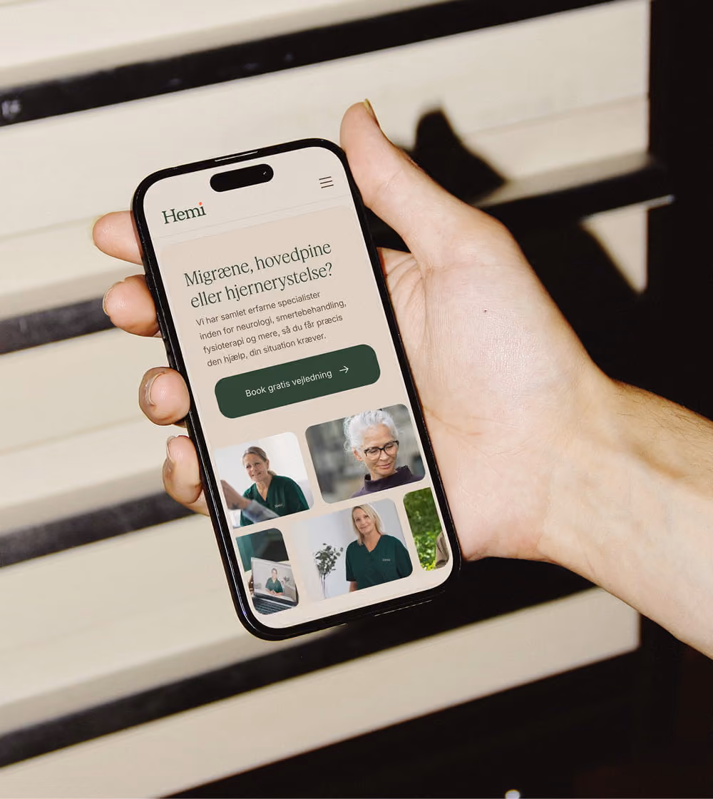 Hånd der holder en smartphone med Hemi Healths website.