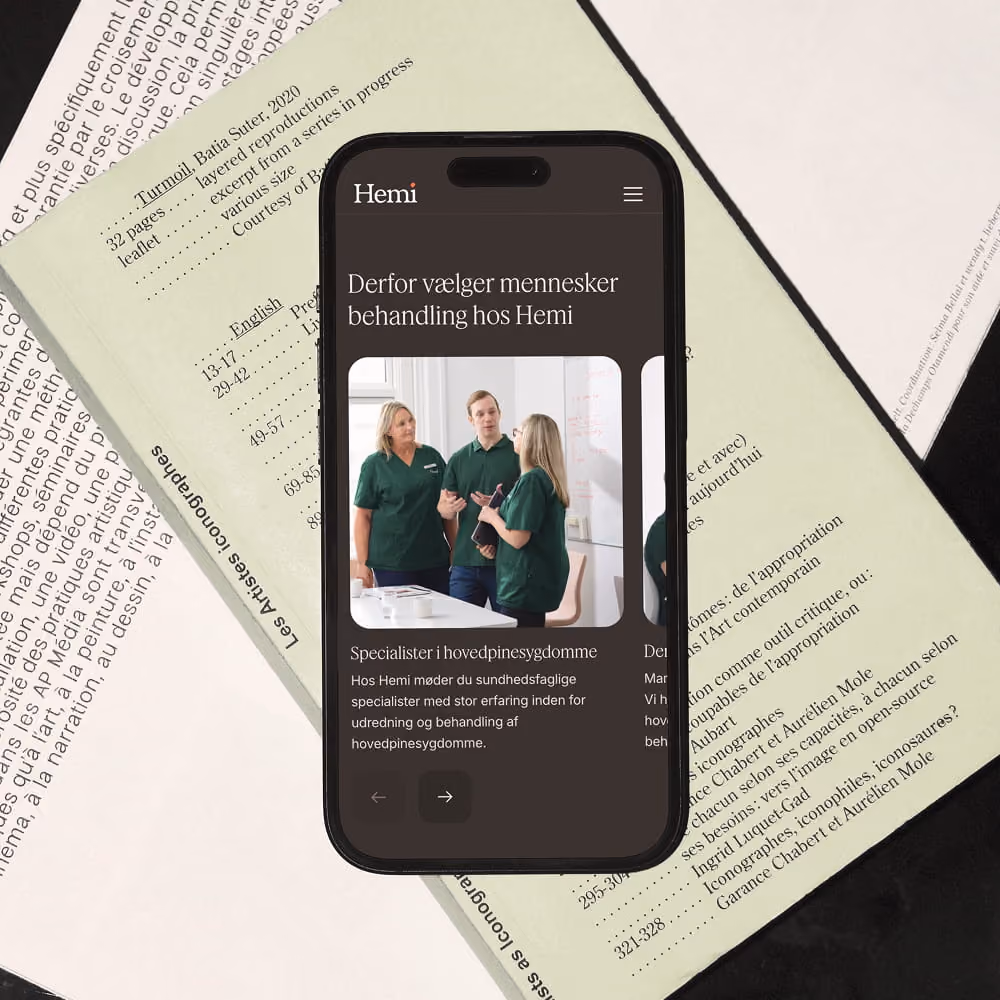 Smartphone med Hemi Healths website i dark mode, placeret på en avis.