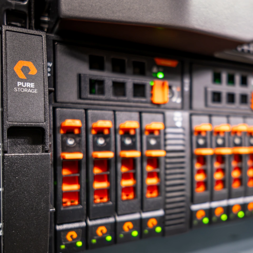 Nahaufnahme eines Pure Storage Servers mit orangefarbenen Komponenten und grünen Statusanzeigen.