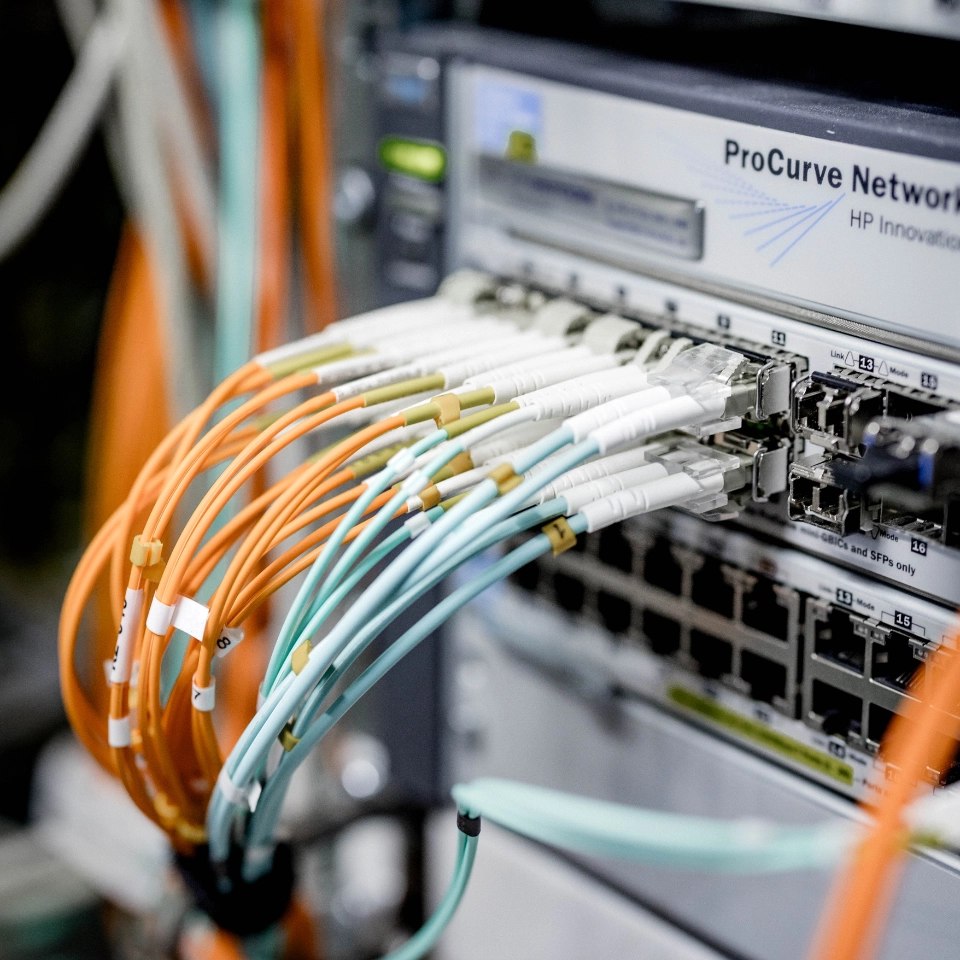 Netzwerk-Switch mit mehreren orangefarbenen und blauen Glasfaserkabeln verbunden.