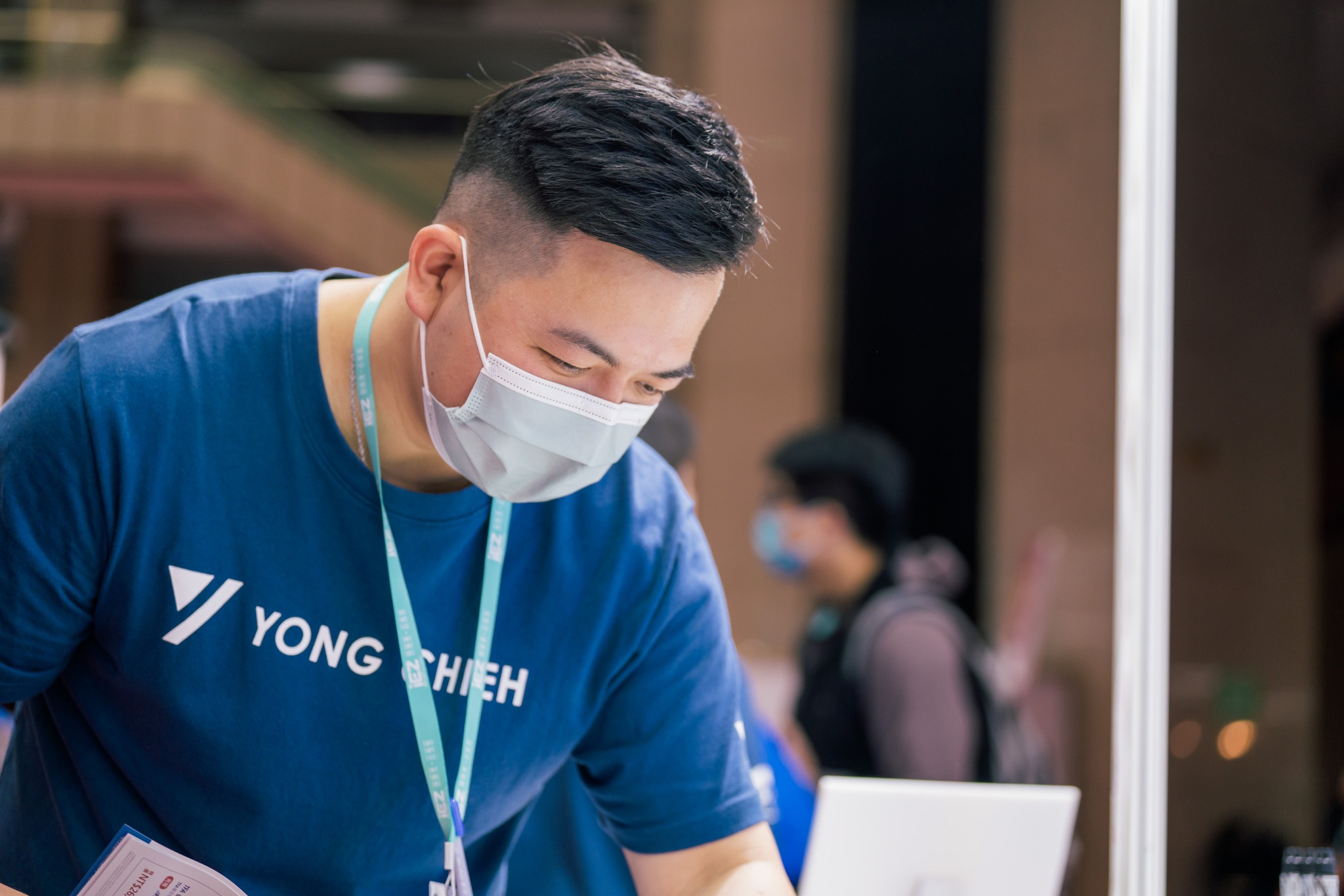 A Yong Chieh team member assists participants at an event