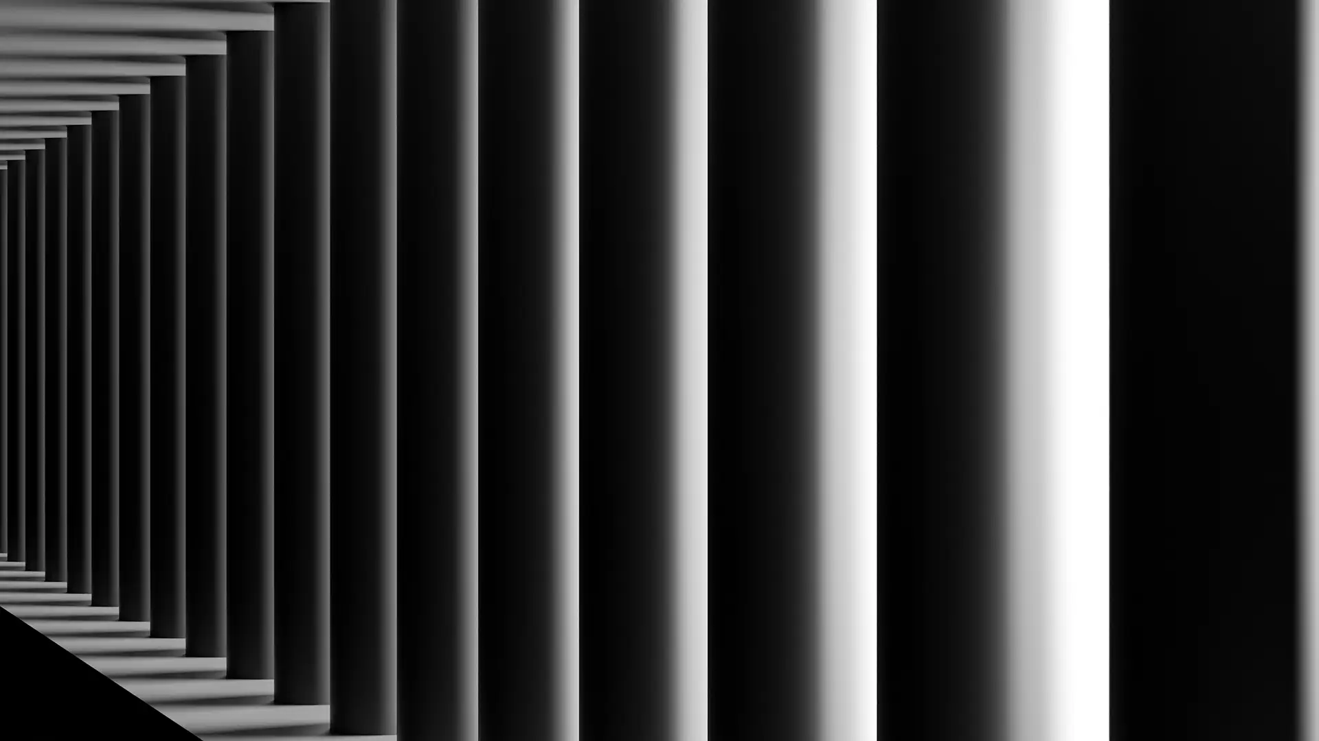 Row of tall cylindrical columns casting long shadows creating a repeating pattern in black and white.