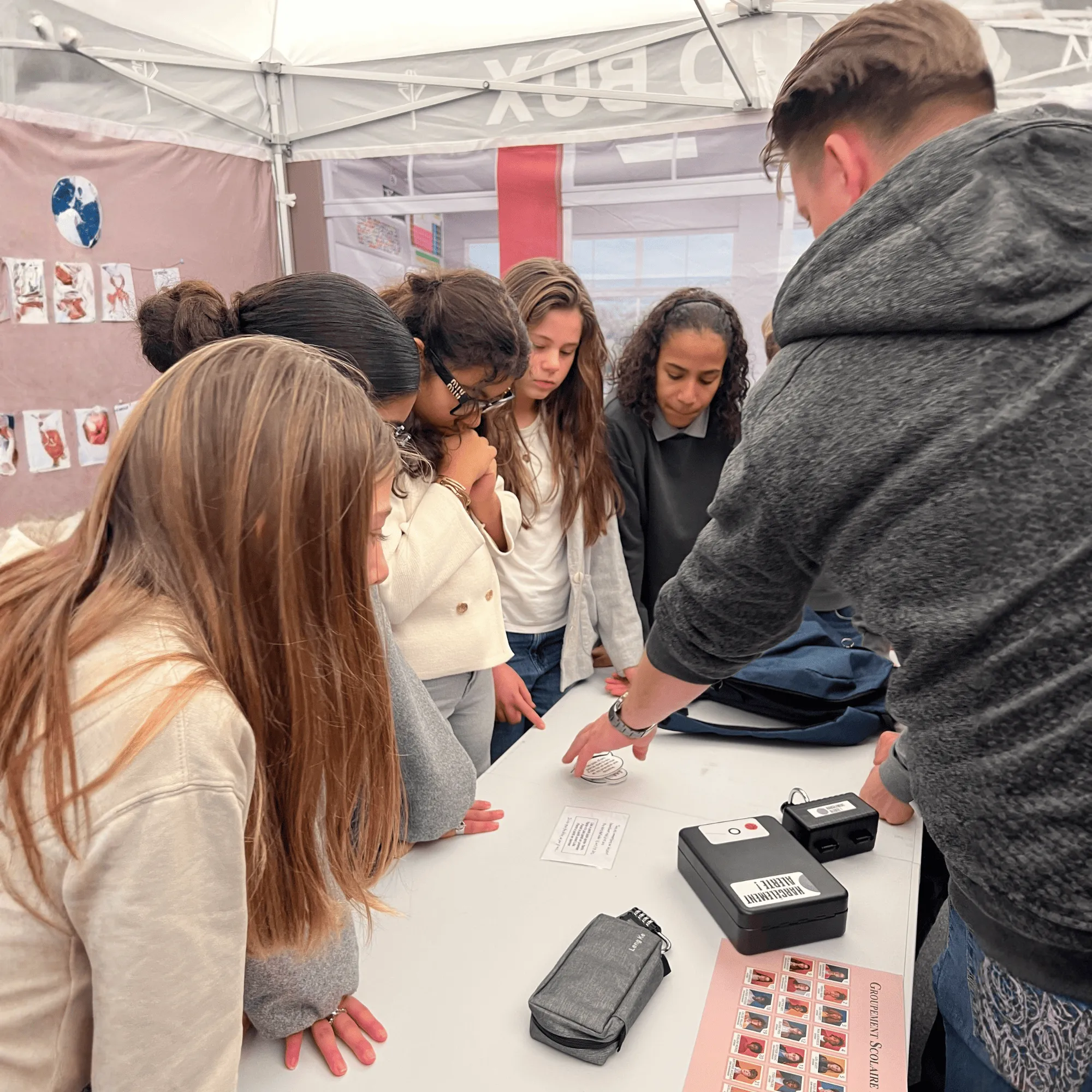 Sensibilisation locked box
Un groupe d'adolescents concentrés autour d'une table sur laquelle se trouvent des documents et des boîtiers électroniques.