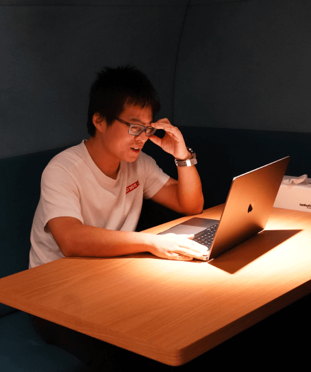 An Audiomob team member using a laptop in an office booth.
