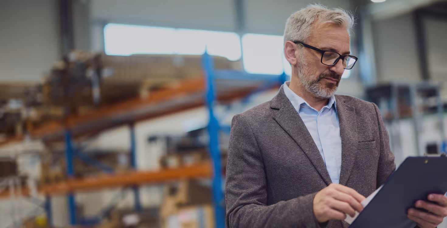 Health and safety consultant reviewing a clipboard in an industrial workplace