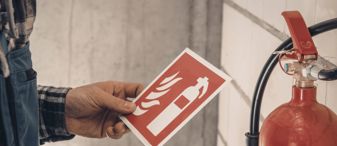 Person posting fire safety signage next to a red fire extinguisher.