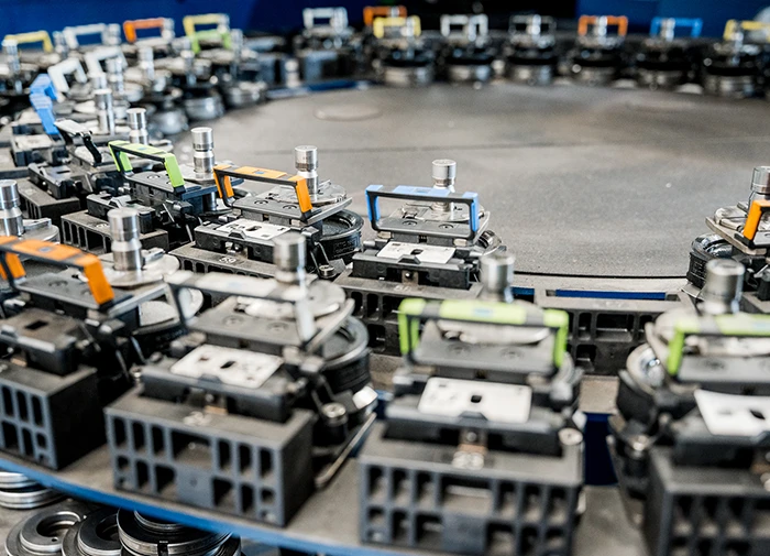 Runde Anordnung automatisierter Greifarme mit farbigen Griffen auf industrieller Maschine.