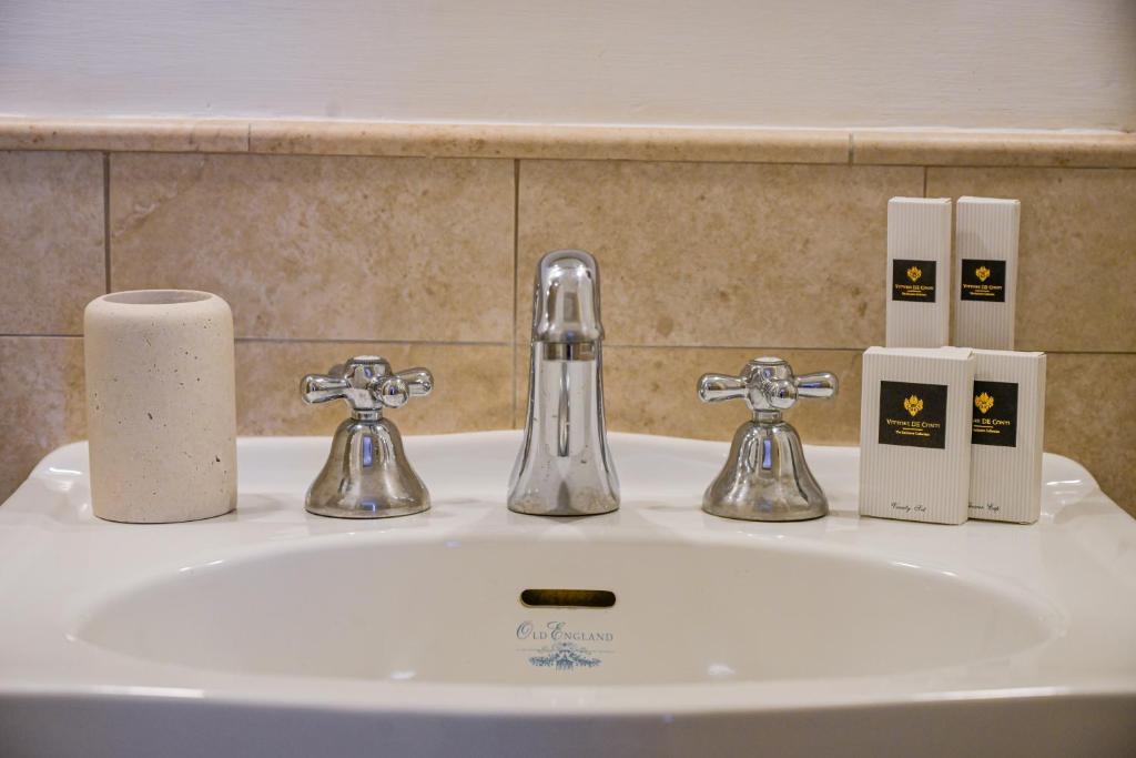 Bathroom sink with silver faucets, a beige holder on the left, and four boxed toiletries stacked on the right.