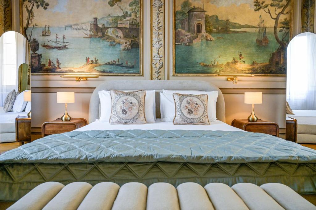 Luxurious bedroom with a large bed featuring elegant floral pillows and a green quilt, flanked by wooden nightstands with gold lamps, set against a backdrop of classical maritime wall murals.