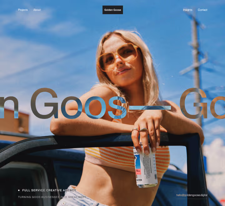 Young woman with sunglasses leaning on a car door holding a beverage can under blue sky.