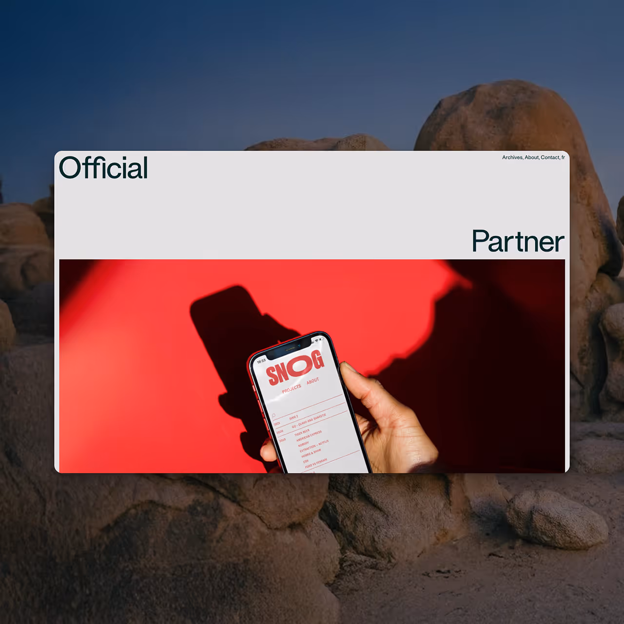 A hand holding a smartphone displaying a website with the logo SNOG and a project list on a red background.