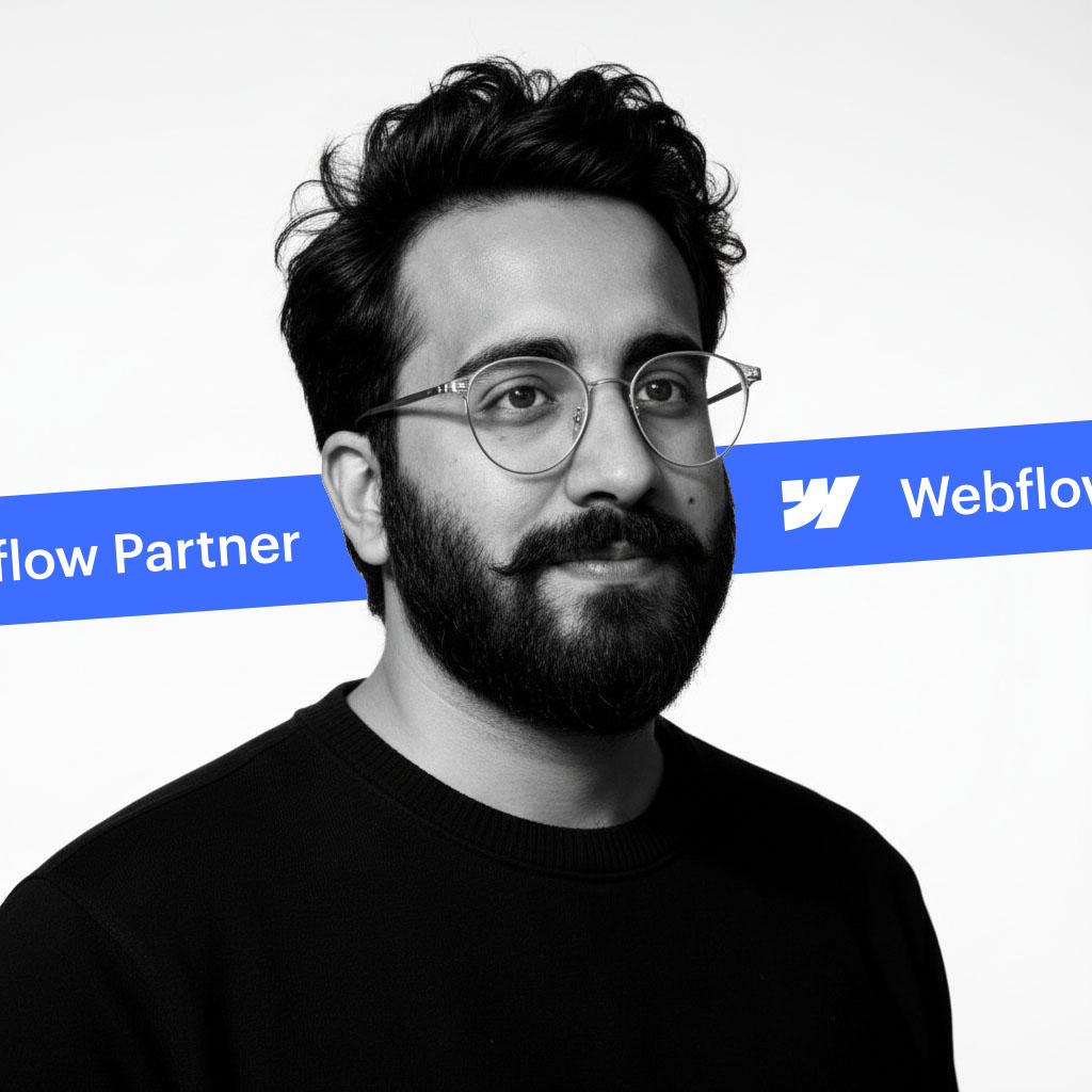 Portrait of a bearded man with glasses in a black shirt, with a blue Webflow Partner banner behind him.