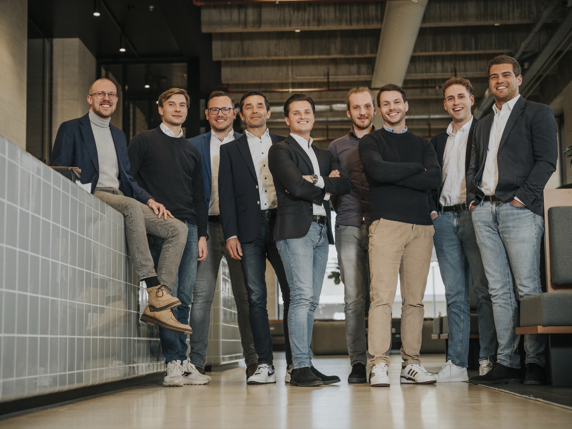 Twee personen kijken vanuit een glazen balkon uit op een magazijn met werkers, automatisering en transportbanden.