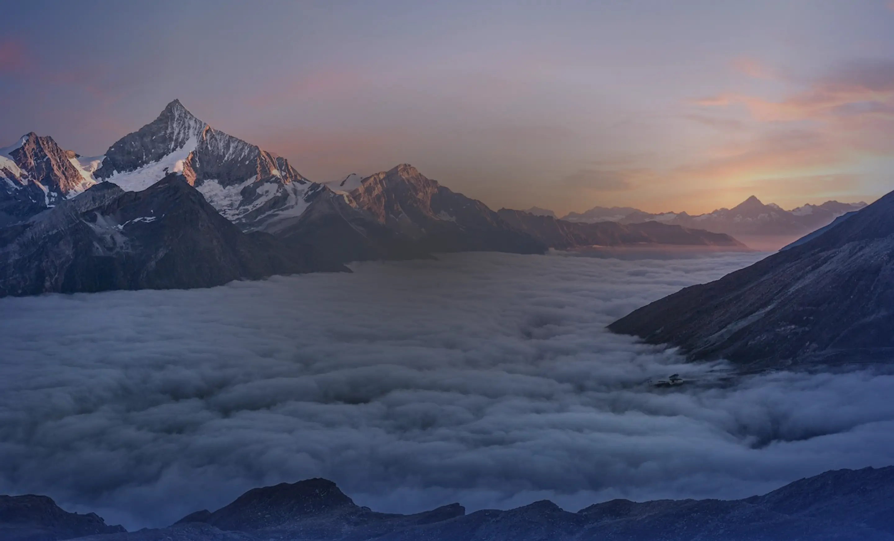 Bergtoppen boven een wolkenzee bij zonsondergang