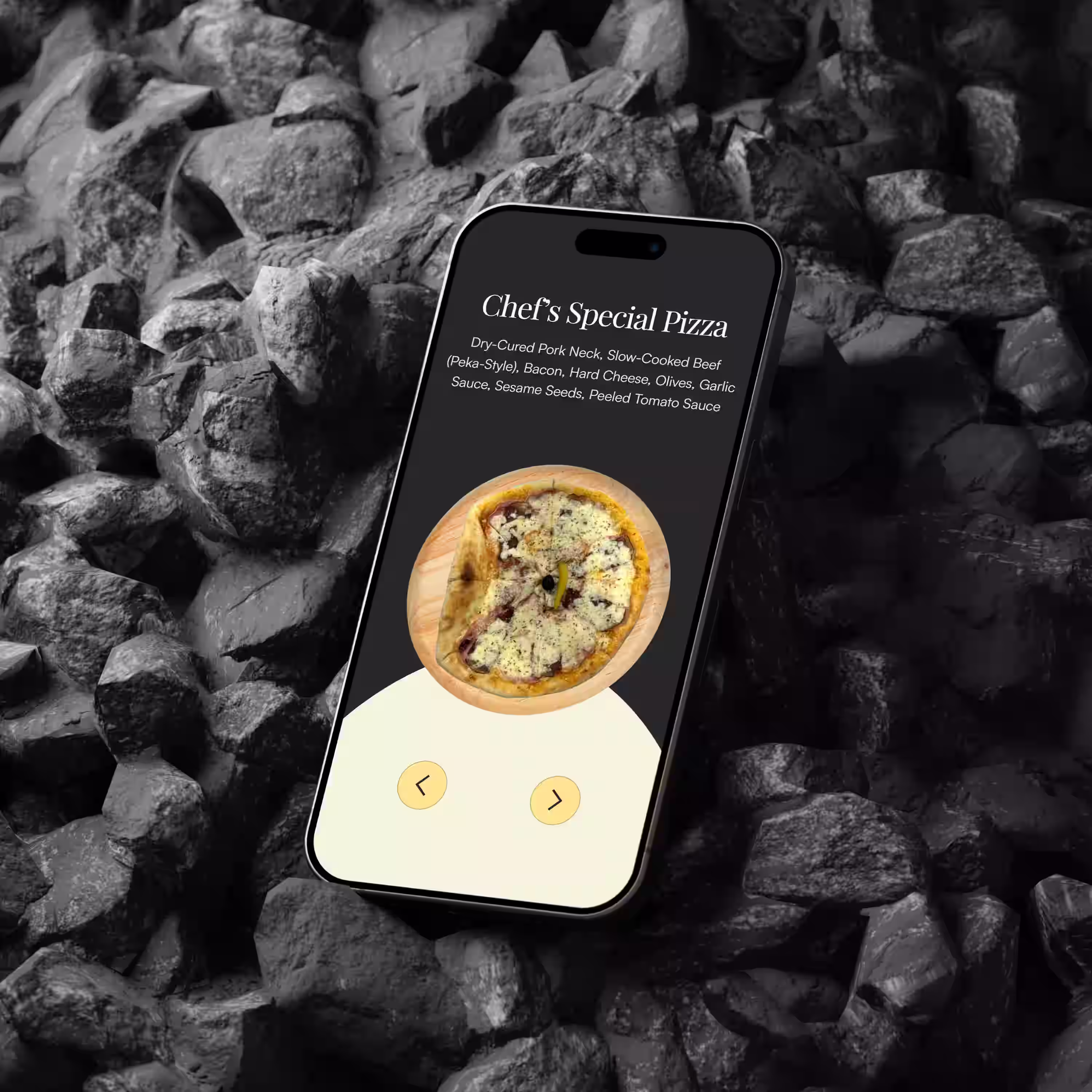 Smartphone screen displaying a Chef's Special Pizza menu with a pizza image and navigation arrows, placed on dark rocks.