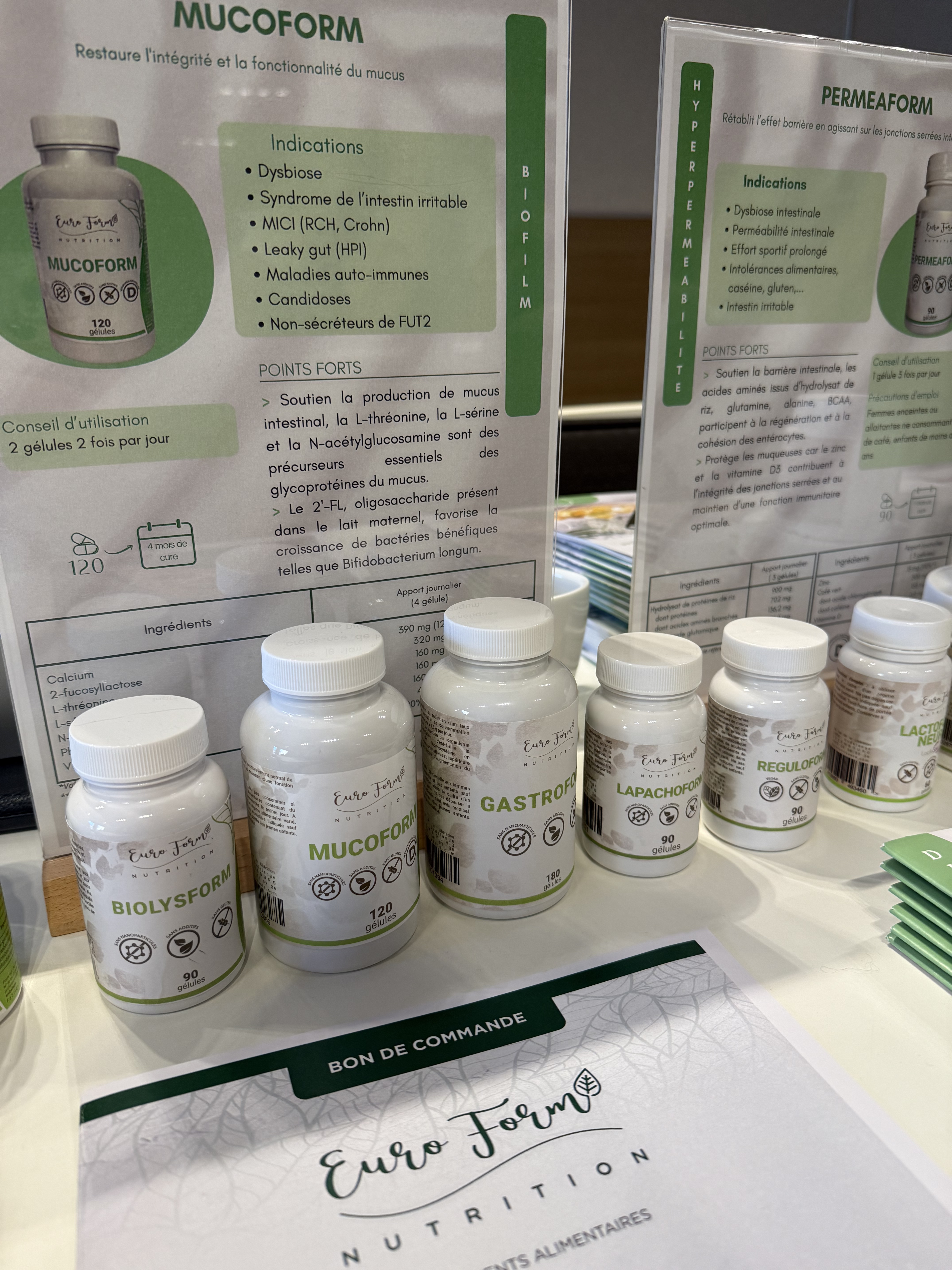 Bottles of Euro Form Nutrition supplements on a table with informational posters in the background.