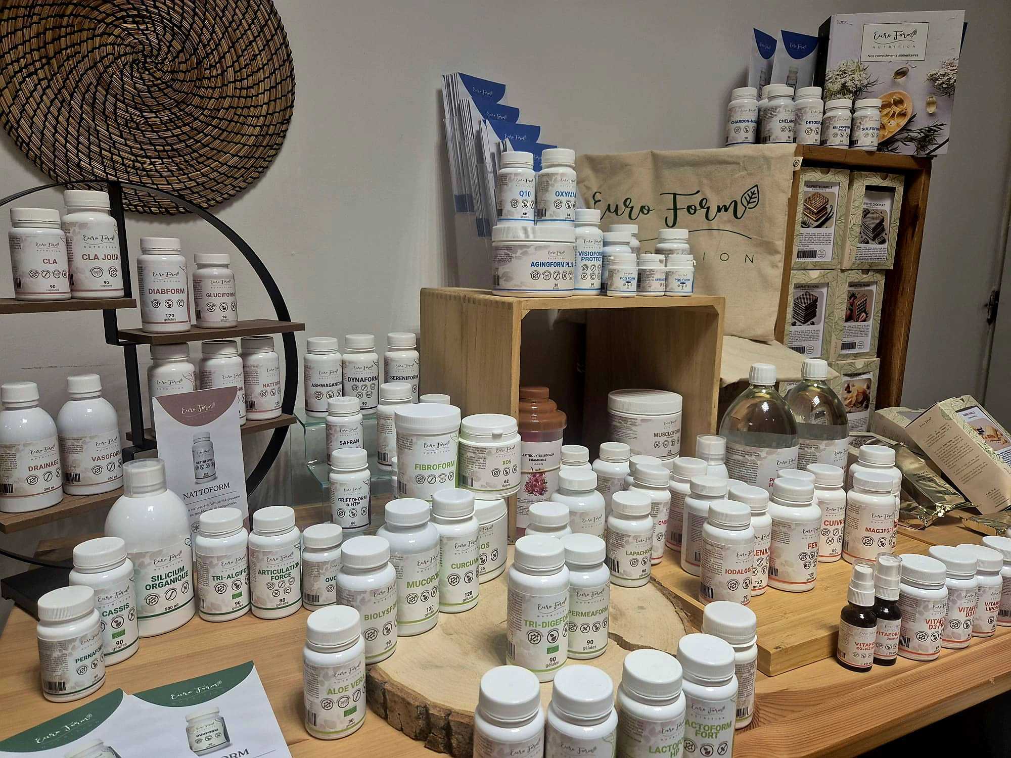 Various nutritional supplements and vitamin bottles displayed on wooden shelves and table surface.