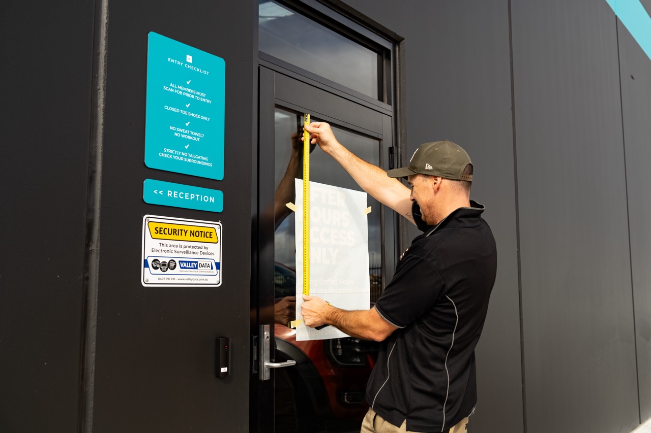 A man named Michael Cox sign writing a door with a sticker