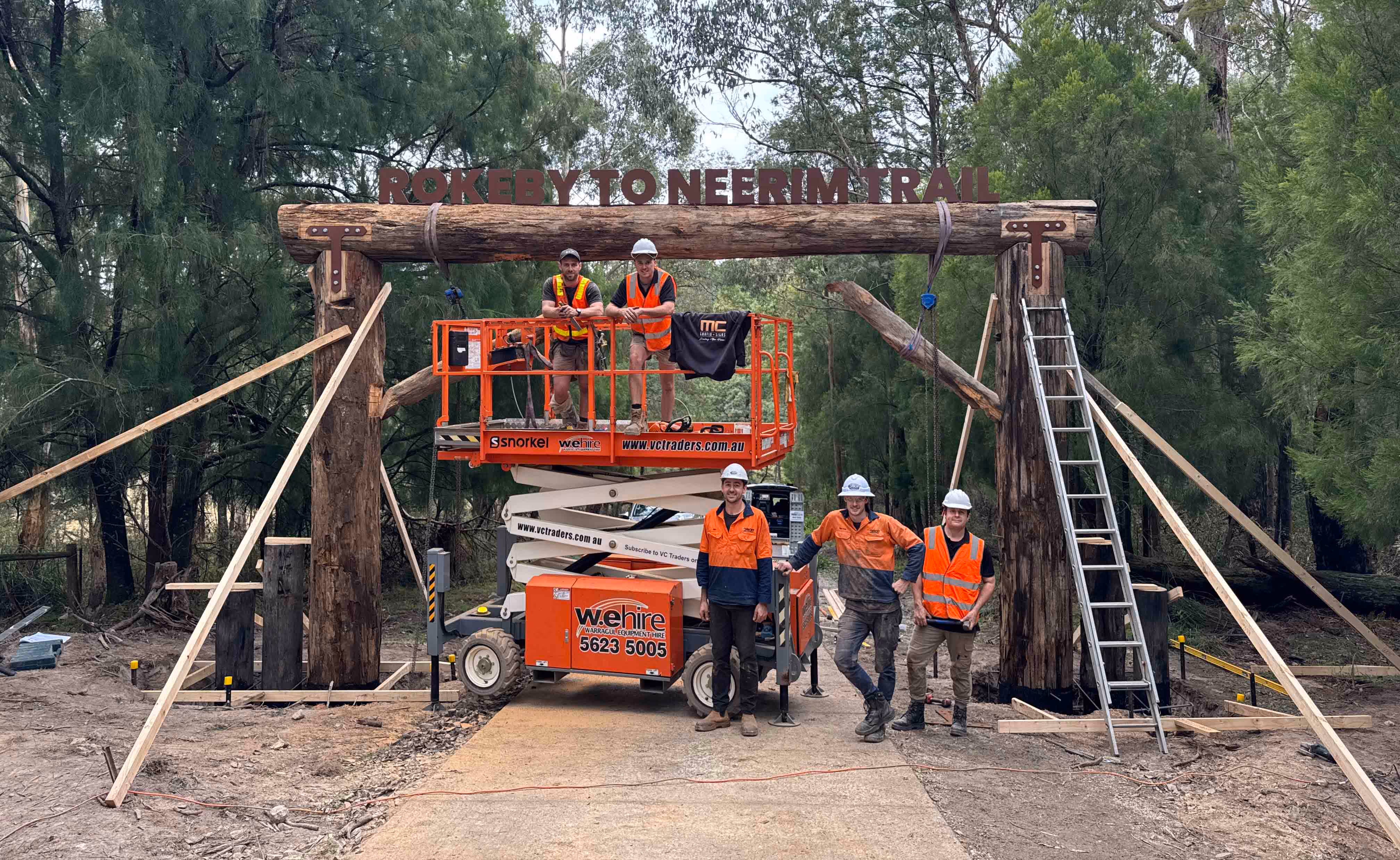 5 men standing infront of a sign they've just built out of tree logs and 3d cut metal signage. The sign reads Rokeby to Neerim Trail