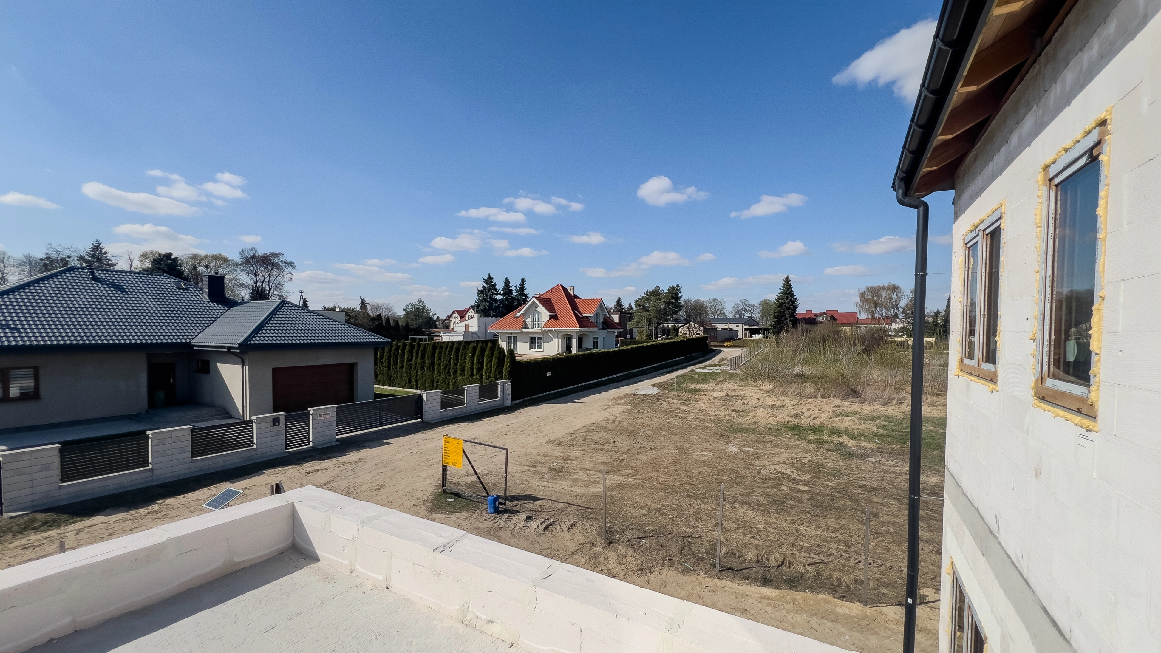 Widok z góry na układ domu z salonami, kuchniami, łazienkami i garażem z zaparkowanym samochodem.
