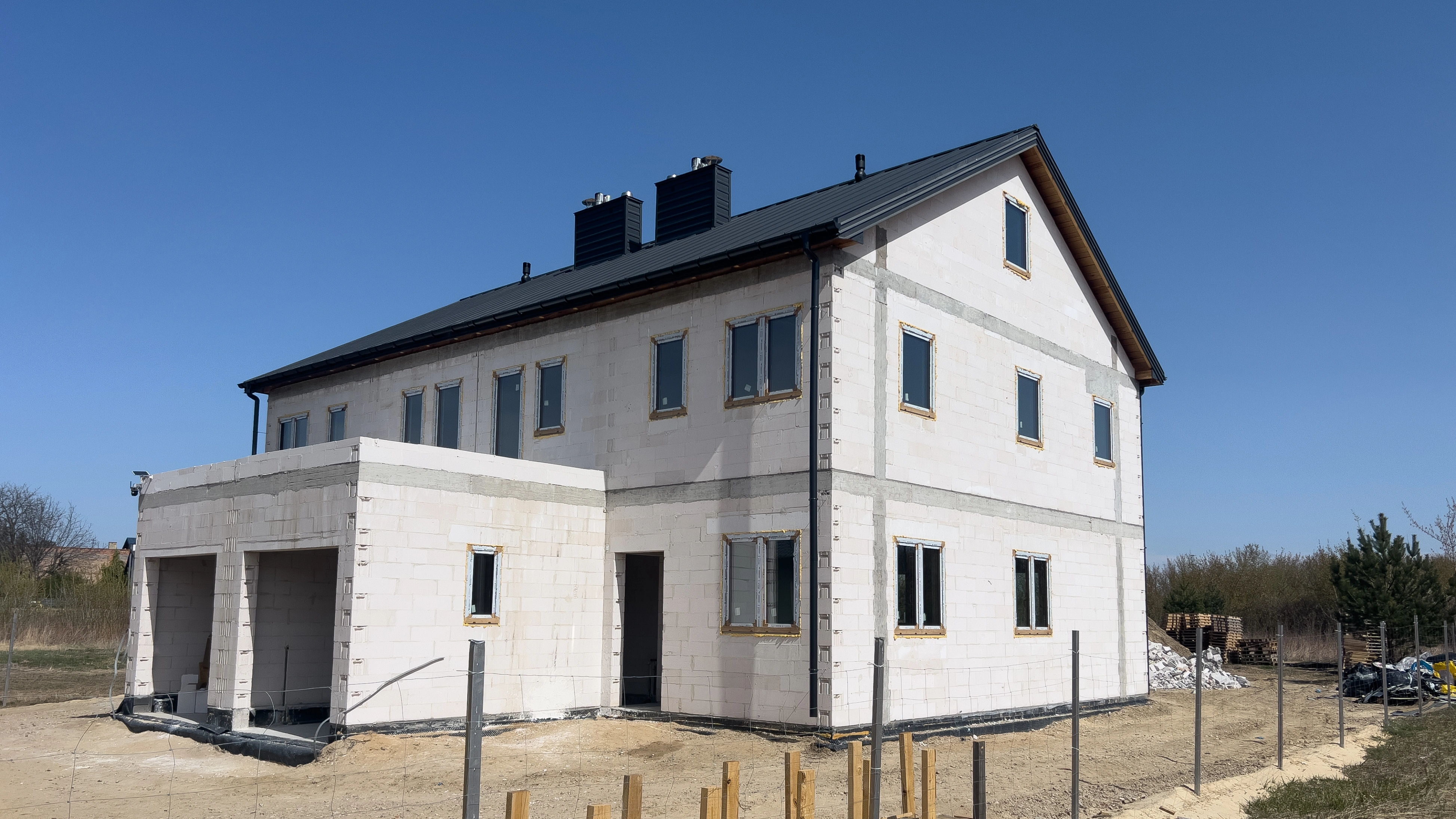 Widok z góry na układ domu z salonami, kuchniami, łazienkami i garażem z zaparkowanym samochodem.