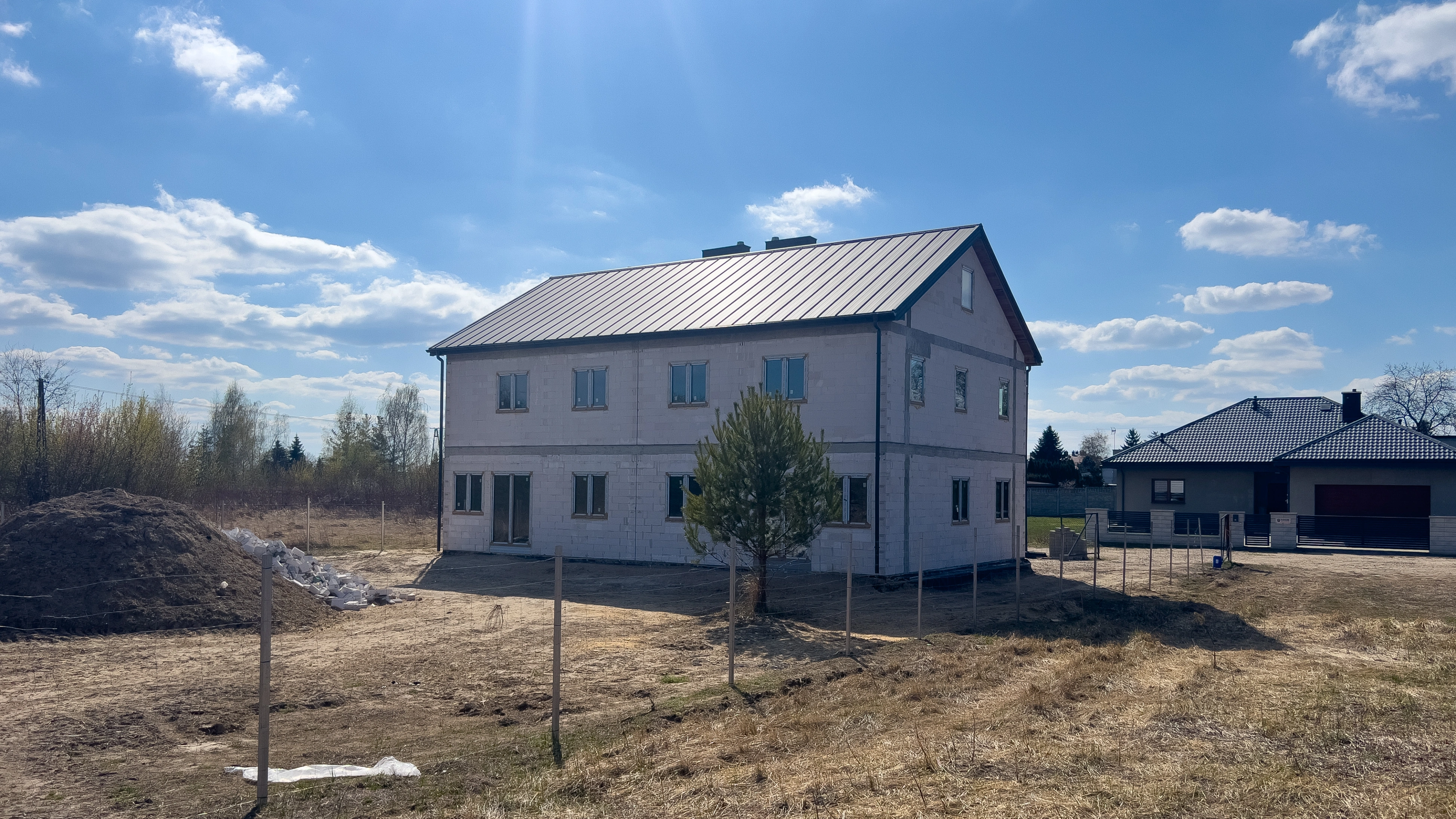 Widok z góry na układ domu z salonami, kuchniami, łazienkami i garażem z zaparkowanym samochodem.