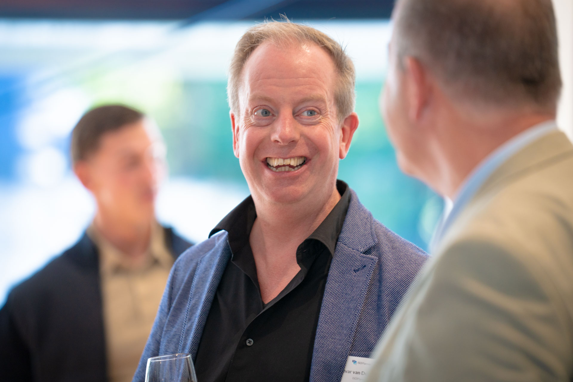 Two men stand close together, one smiling broadly while talking with the other during the reception.
