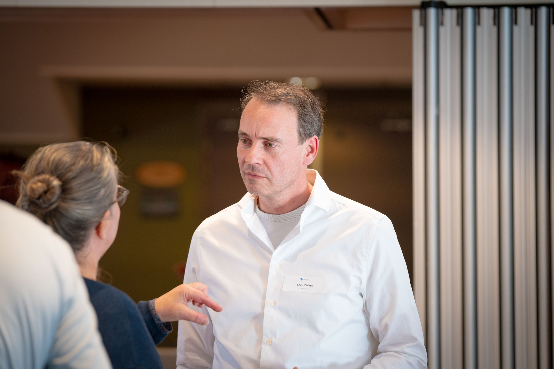 A man speaks with a woman during the networking reception, both engaged in conversation.