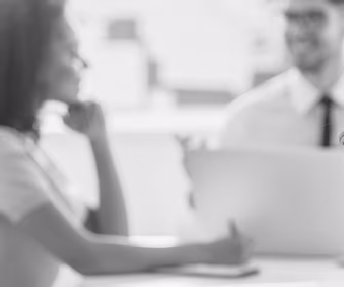 Blurry black and white photo of two people sitting at a table, talking and smiling.