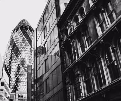 Black and white photo of London buildings including the modern Gherkin tower and older stone facades.