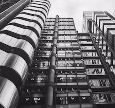 Black and white photo of modern multi-story buildings with glass windows and metal pipes.